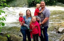 The Miller family poses together outside in front of a stream.